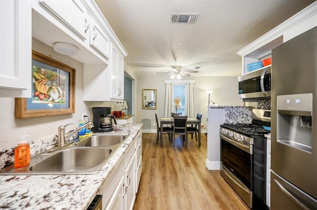 kitchen featuring visible vents, a ceiling fan, appliances with stainless steel finishes, white cabinetry, and a sink