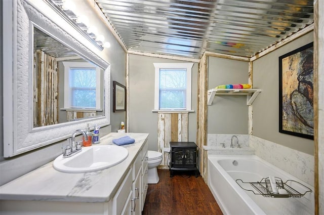 bathroom featuring vanity, a wood stove, toilet, a garden tub, and wood finished floors