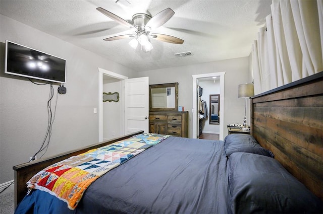 bedroom with visible vents, a ceiling fan, a walk in closet, and a textured ceiling