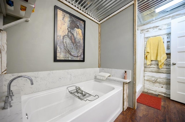 bathroom featuring wood finished floors and a bath