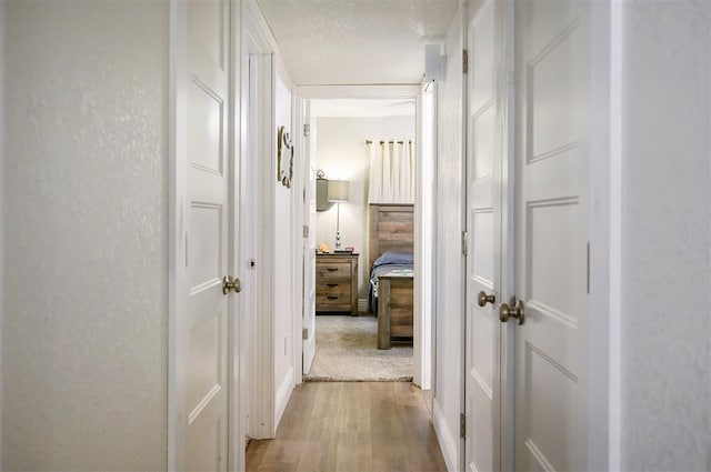 hall with a textured ceiling and wood finished floors