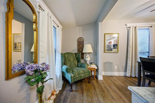 sitting room with a textured ceiling, baseboards, and wood finished floors
