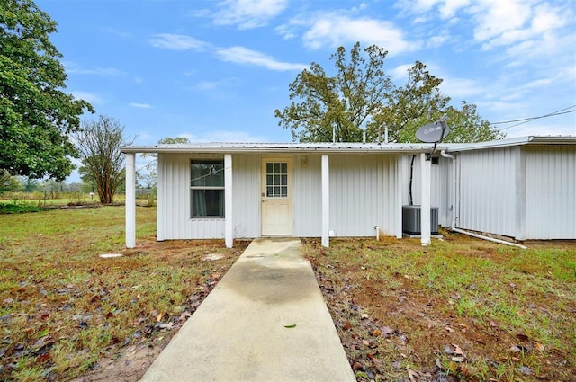 exterior space featuring metal roof, central AC unit, and a lawn