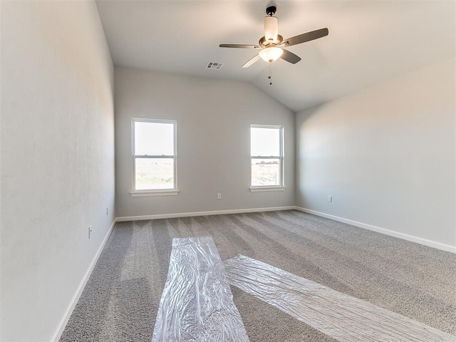 carpeted spare room featuring a wealth of natural light, ceiling fan, and lofted ceiling