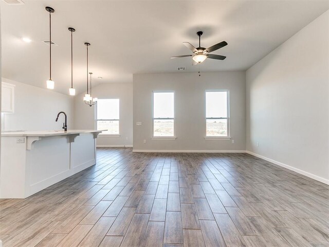 interior space with light wood-type flooring, ceiling fan with notable chandelier, a healthy amount of sunlight, and sink