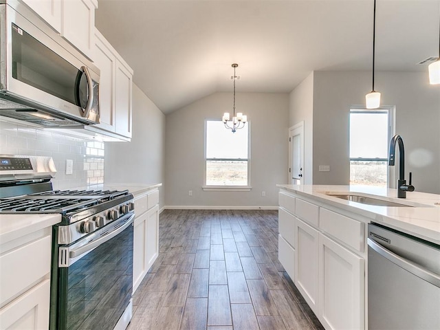 kitchen featuring appliances with stainless steel finishes, dark wood-type flooring, sink, white cabinetry, and lofted ceiling