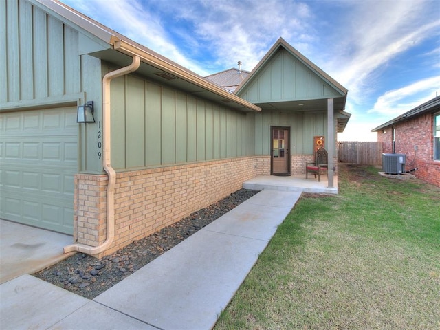 doorway to property featuring a yard, a garage, and central air condition unit