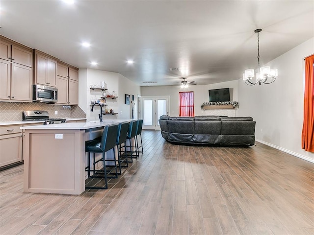 kitchen featuring light hardwood / wood-style floors, an island with sink, appliances with stainless steel finishes, and a breakfast bar area