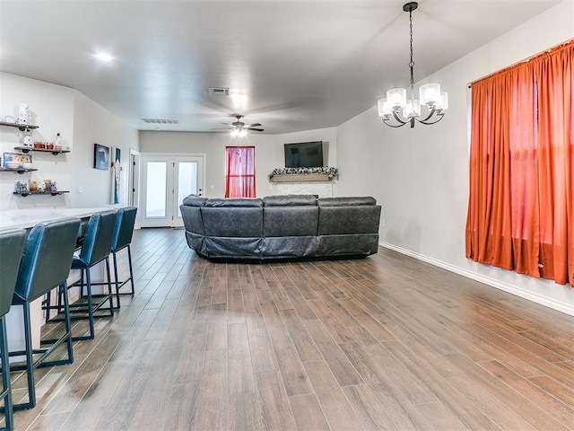 living room with hardwood / wood-style floors, ceiling fan with notable chandelier, and french doors