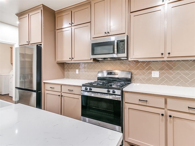 kitchen featuring appliances with stainless steel finishes, separate washer and dryer, and tasteful backsplash