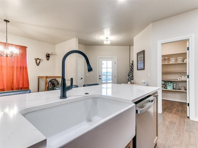 kitchen featuring light wood-type flooring, sink, dishwasher, a chandelier, and hanging light fixtures