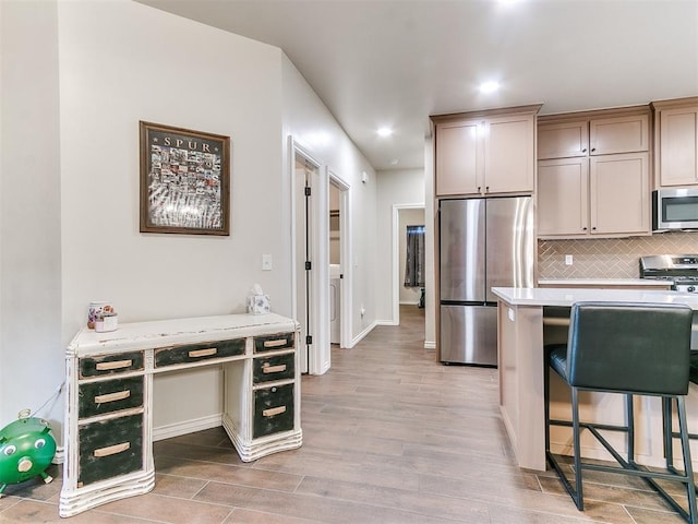 kitchen with stainless steel appliances, light hardwood / wood-style flooring, tasteful backsplash, and a breakfast bar area