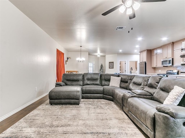 living room with hardwood / wood-style floors, ceiling fan with notable chandelier, and sink