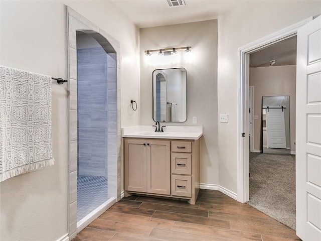 bathroom featuring a tile shower, vanity, and hardwood / wood-style flooring