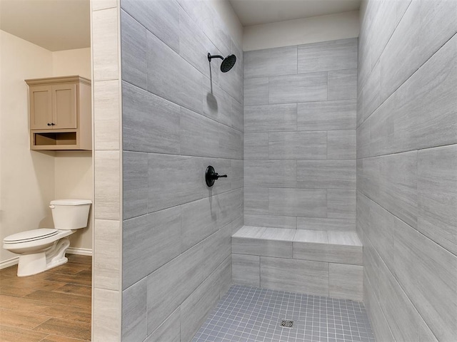 bathroom with hardwood / wood-style flooring, toilet, and tiled shower