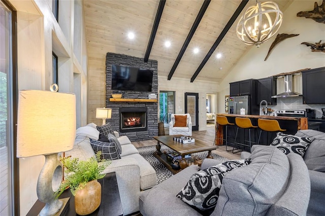 living room featuring beam ceiling, high vaulted ceiling, a notable chandelier, a fireplace, and wood ceiling