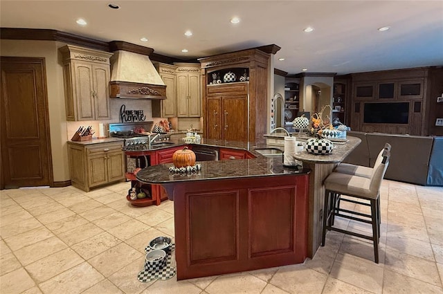 kitchen with a large island with sink, sink, ornamental molding, custom range hood, and a breakfast bar area