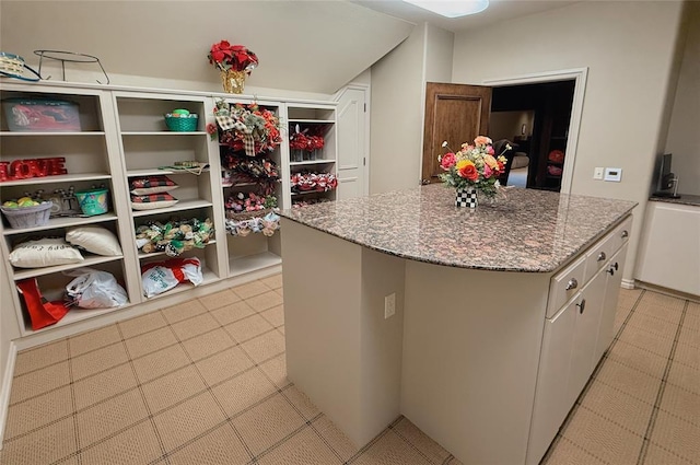 kitchen with white cabinetry, a kitchen island, and dark stone countertops