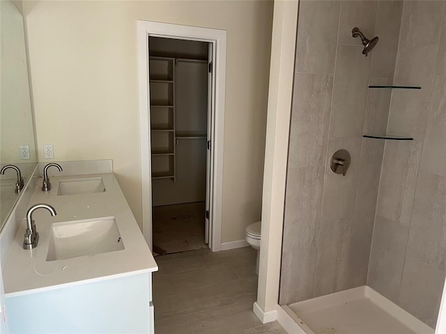 bathroom with toilet, tiled shower, and vanity