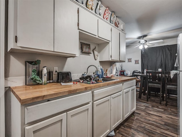 kitchen with white cabinets, butcher block countertops, sink, and dark wood-type flooring