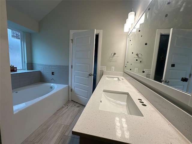 bathroom with vanity, lofted ceiling, and a bath