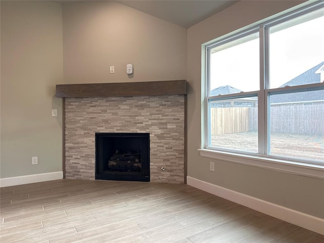 unfurnished living room featuring light wood-type flooring, a fireplace, and a wealth of natural light