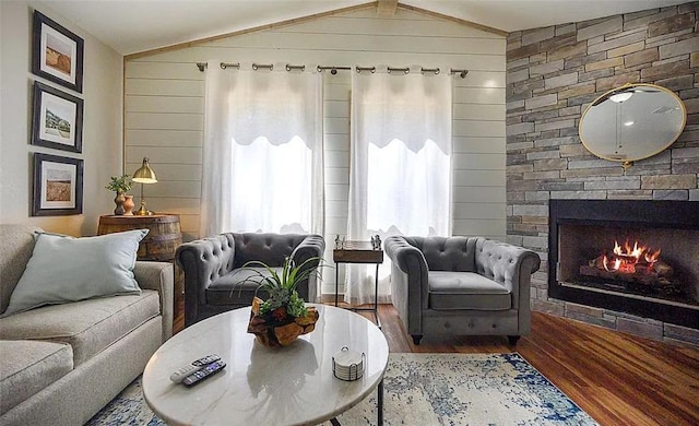 living room featuring wood-type flooring, a fireplace, wooden walls, and vaulted ceiling