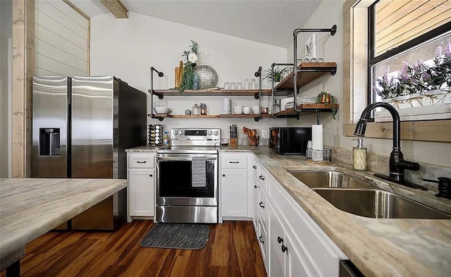 kitchen featuring white cabinets, vaulted ceiling with beams, sink, and stainless steel appliances