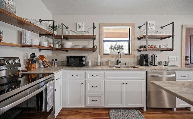 kitchen with white cabinetry, sink, light stone counters, dark hardwood / wood-style flooring, and appliances with stainless steel finishes