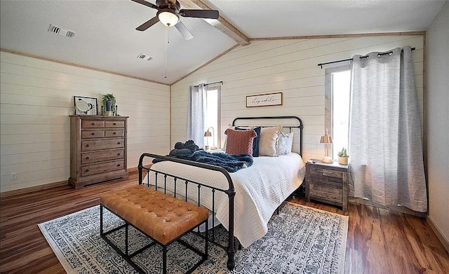 bedroom with ceiling fan, lofted ceiling with beams, dark wood-type flooring, and multiple windows