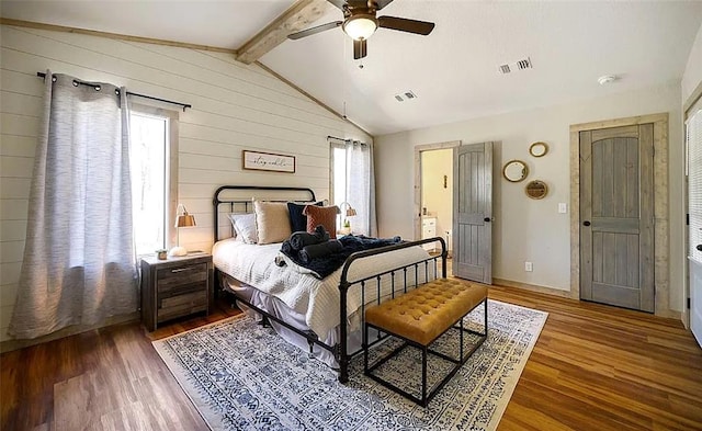 bedroom featuring hardwood / wood-style flooring, ceiling fan, lofted ceiling with beams, and wooden walls