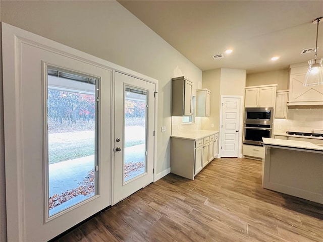 kitchen featuring decorative backsplash, appliances with stainless steel finishes, light wood-type flooring, gray cabinetry, and pendant lighting