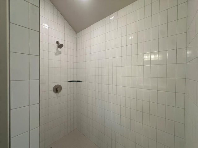 bathroom with tiled shower and vaulted ceiling