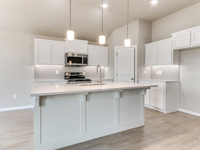 kitchen with hanging light fixtures, a center island with sink, and stainless steel appliances