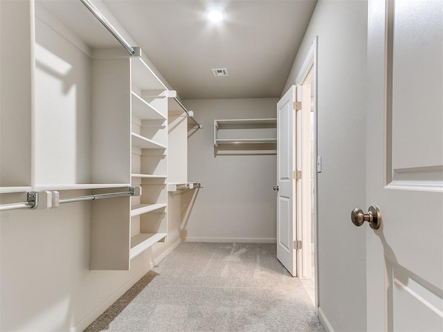 walk in closet with light carpet