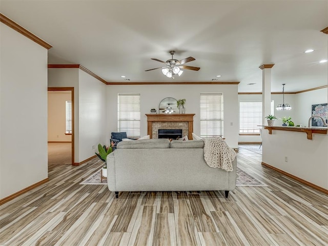 living room with ceiling fan with notable chandelier, light hardwood / wood-style floors, a wealth of natural light, and ornamental molding