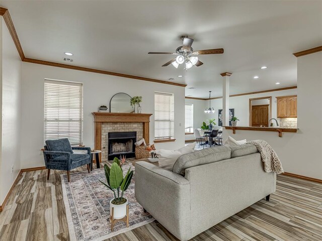 living room featuring a fireplace, plenty of natural light, light hardwood / wood-style floors, and ornamental molding