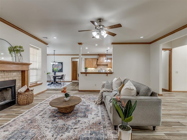 living room with a fireplace, light hardwood / wood-style flooring, ceiling fan, and ornamental molding