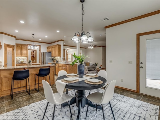 dining space featuring ceiling fan with notable chandelier, ornamental molding, and sink