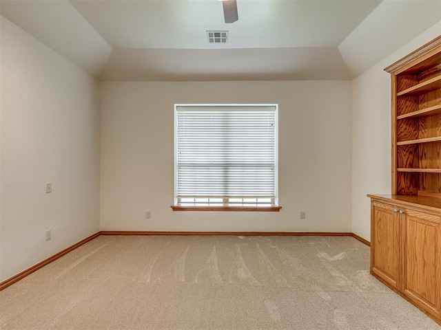 empty room featuring ceiling fan, lofted ceiling, light carpet, and built in shelves