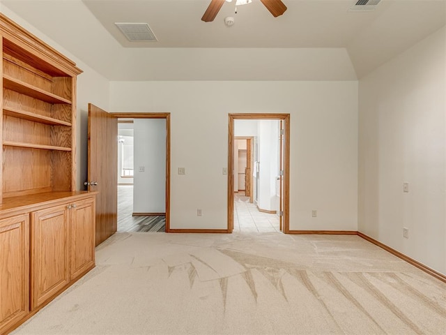 unfurnished bedroom featuring ensuite bath, light colored carpet, vaulted ceiling, and ceiling fan