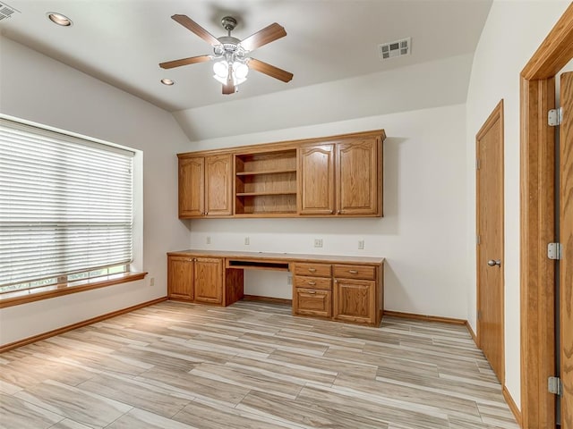 unfurnished office with ceiling fan, built in desk, and lofted ceiling