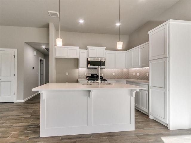 kitchen with pendant lighting, a center island with sink, white cabinets, and stainless steel appliances