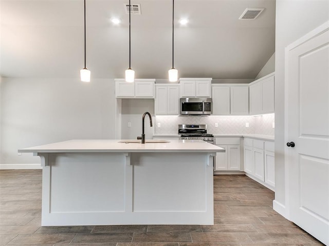 kitchen with decorative light fixtures, sink, white cabinetry, and stainless steel appliances