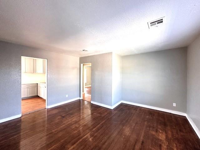 unfurnished room with a textured ceiling and hardwood / wood-style flooring