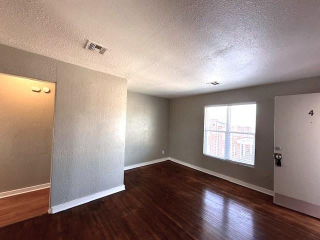 empty room featuring a textured ceiling and dark hardwood / wood-style floors