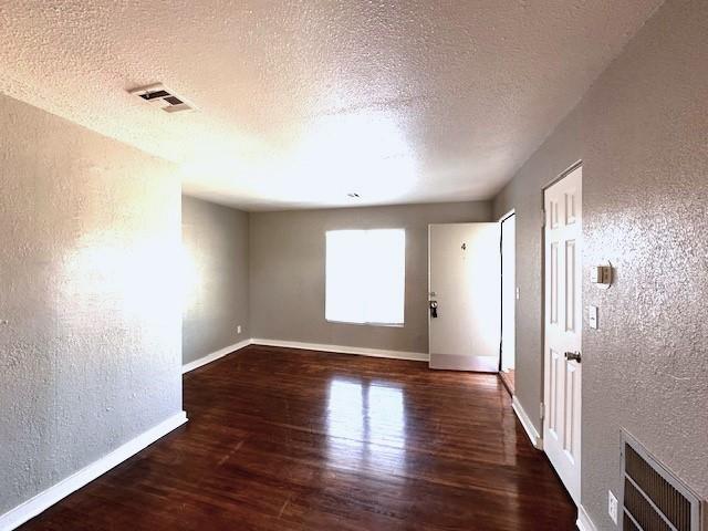 unfurnished room with dark hardwood / wood-style flooring and a textured ceiling