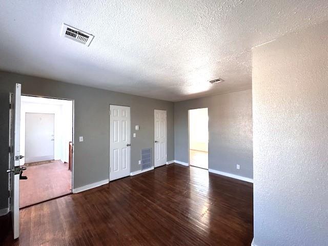 unfurnished room with dark wood-type flooring and a textured ceiling