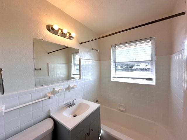 full bathroom with vanity, toilet, tile walls, and tiled shower / bath combo