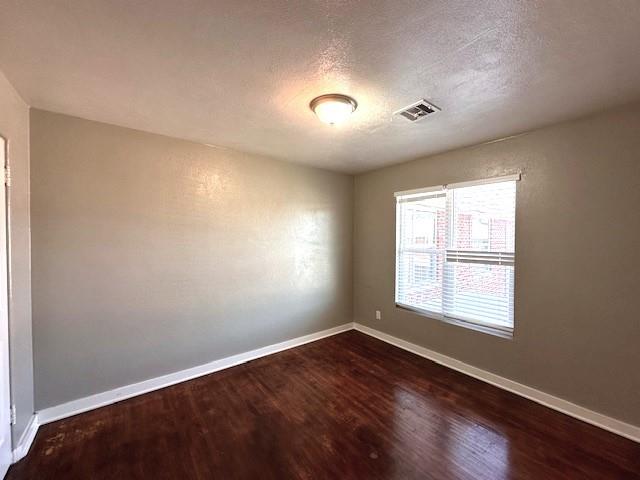 empty room with hardwood / wood-style floors and a textured ceiling